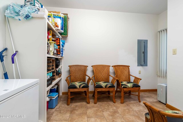 living area with baseboards and electric panel