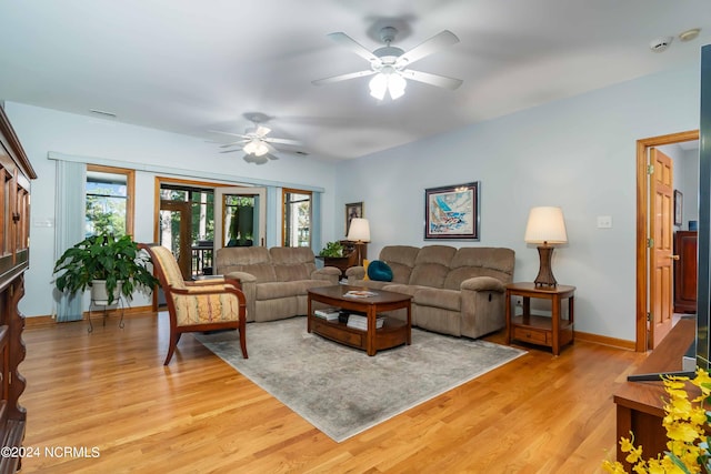 living area featuring baseboards, light wood-type flooring, and ceiling fan