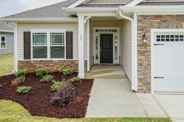 doorway to property featuring a garage, stone siding, and a shingled roof