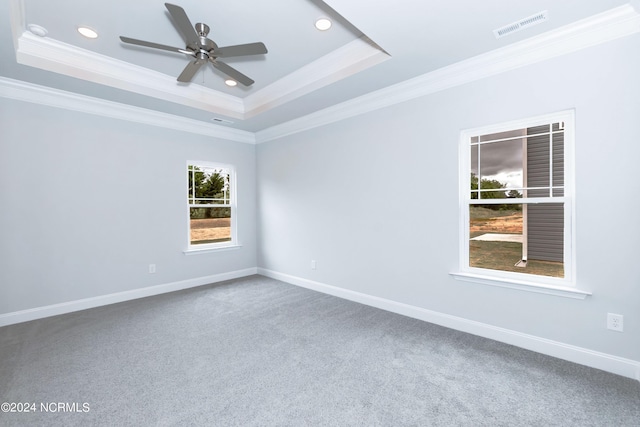 carpeted spare room with ceiling fan, crown molding, and a tray ceiling