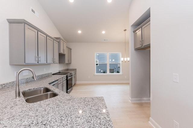 kitchen featuring lofted ceiling, light wood-type flooring, light stone counters, stainless steel appliances, and sink