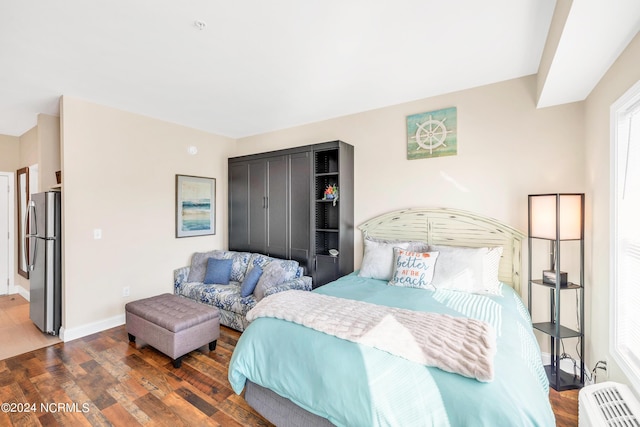 bedroom with dark hardwood / wood-style floors and stainless steel refrigerator