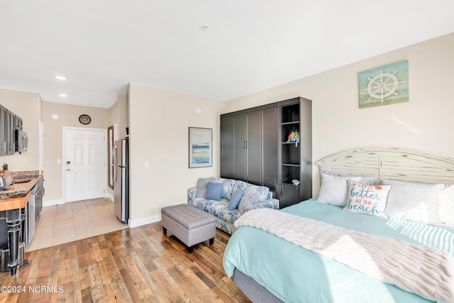 bedroom featuring light wood-type flooring, stainless steel refrigerator, and a closet