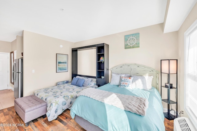 bedroom with stainless steel refrigerator and hardwood / wood-style flooring