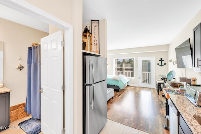 kitchen with appliances with stainless steel finishes, light hardwood / wood-style flooring, and light stone countertops