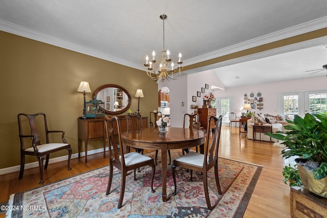 dining space with crown molding, ceiling fan with notable chandelier, lofted ceiling, and light hardwood / wood-style floors