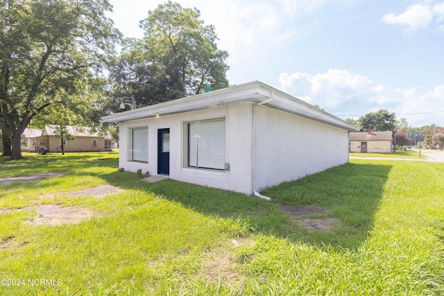 back of property featuring a lawn and concrete block siding