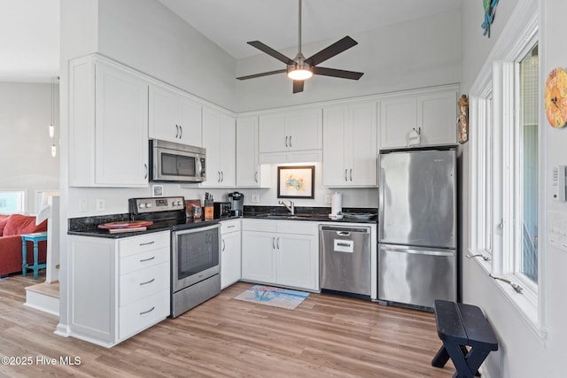 kitchen featuring a sink, dark countertops, white cabinetry, a ceiling fan, and appliances with stainless steel finishes