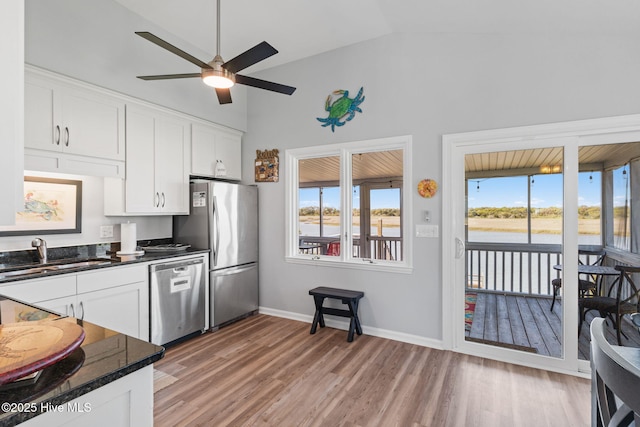 kitchen featuring dark countertops, lofted ceiling, appliances with stainless steel finishes, and a sink