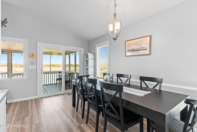 dining space with baseboards, vaulted ceiling, a notable chandelier, and light wood-style flooring