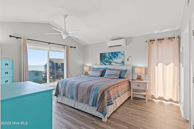 bedroom with lofted ceiling, a ceiling fan, a wall unit AC, and wood finished floors