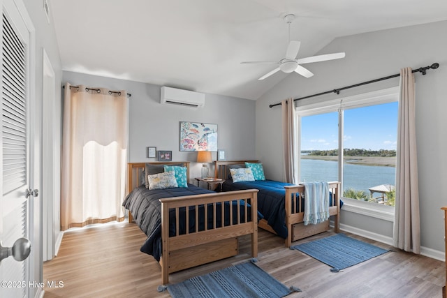 bedroom with a water view, baseboards, light wood-style floors, lofted ceiling, and a wall mounted AC