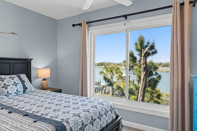 carpeted bedroom with a water view, baseboards, and ceiling fan