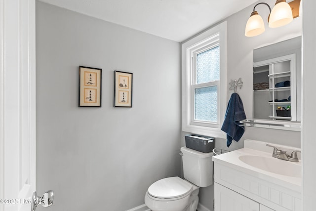 half bathroom with baseboards, vanity, and toilet