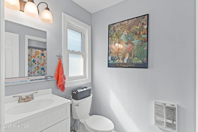 bathroom featuring toilet, vanity, and heating unit