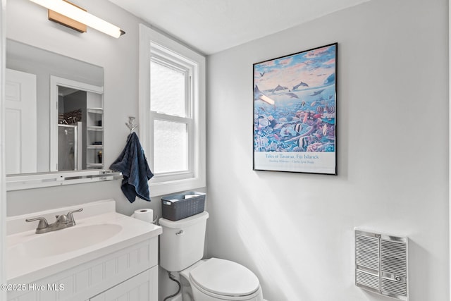 bathroom featuring heating unit, vanity, and toilet