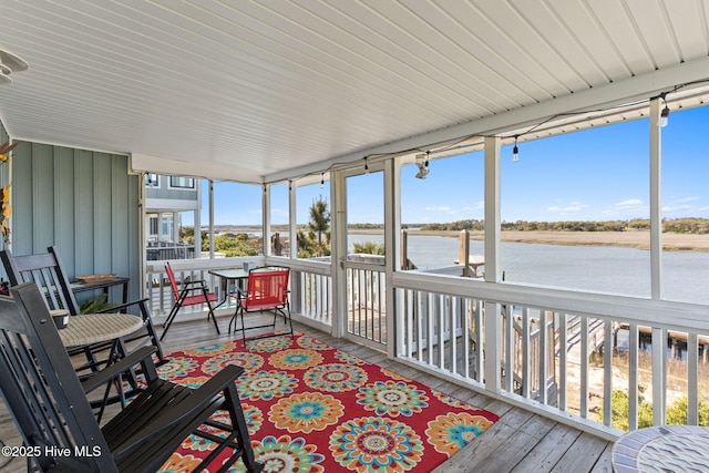 sunroom / solarium with outdoor dining space and a water view
