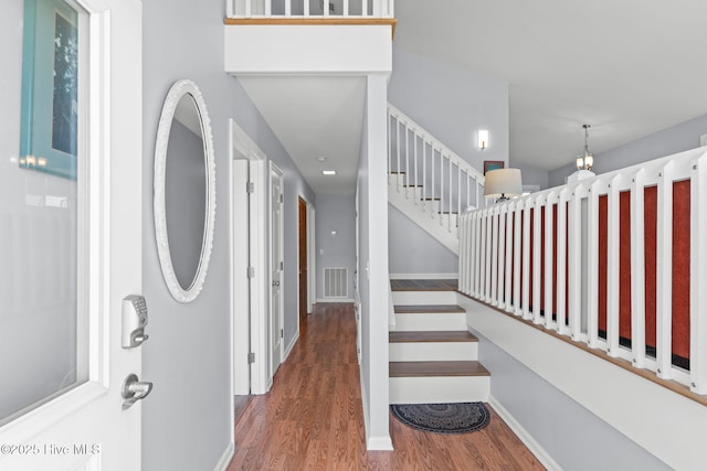 foyer entrance featuring visible vents, baseboards, wood finished floors, and stairs