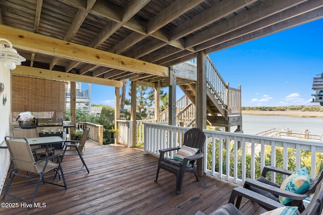 wooden deck featuring stairway, area for grilling, and a water view
