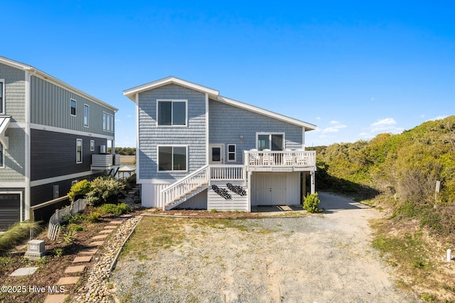 rear view of property with a wooden deck, stairs, and dirt driveway