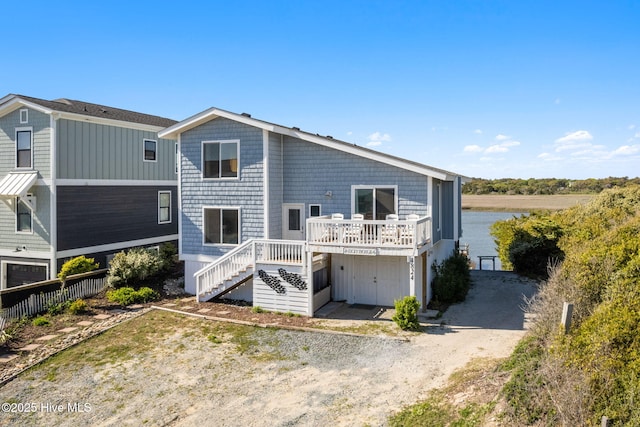 rear view of property featuring dirt driveway, stairway, and a deck