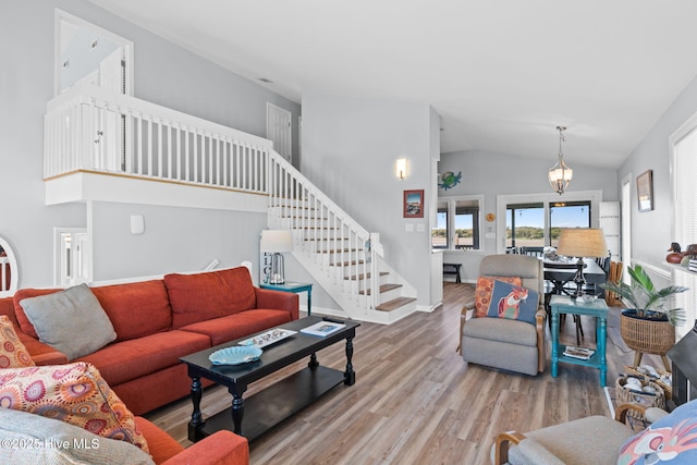 living area featuring lofted ceiling, baseboards, wood finished floors, and stairway