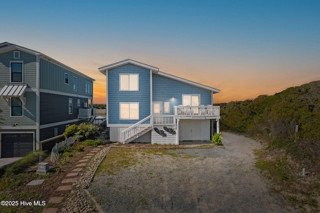 back of property at dusk with stairway and dirt driveway