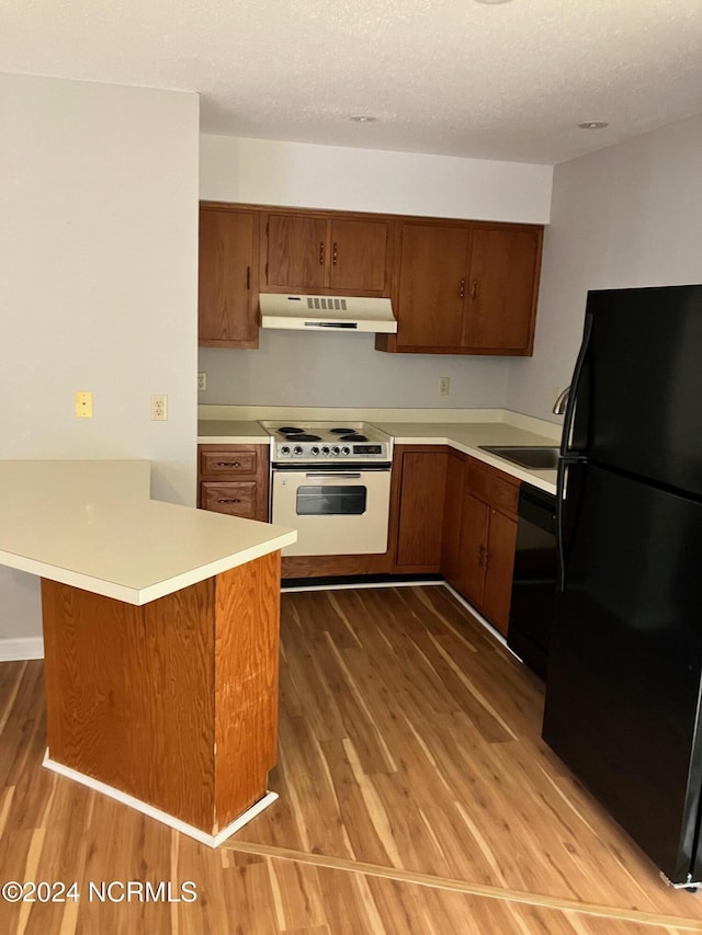 kitchen with under cabinet range hood, dishwasher, freestanding refrigerator, wood finished floors, and electric range