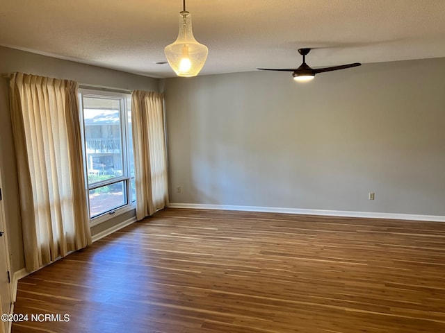 spare room with a textured ceiling, a ceiling fan, baseboards, and wood finished floors