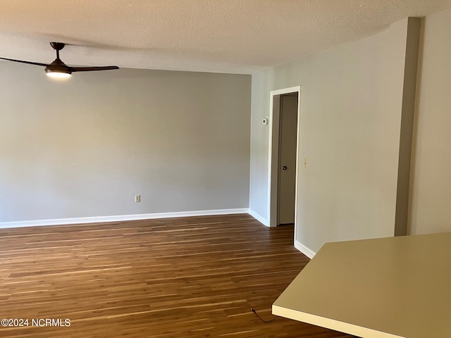 empty room with a ceiling fan, wood finished floors, baseboards, and a textured ceiling