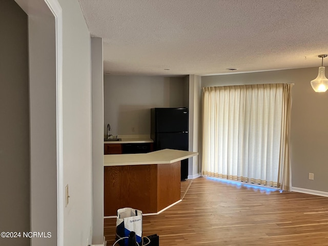 kitchen featuring light countertops, light wood-style floors, freestanding refrigerator, and a textured ceiling