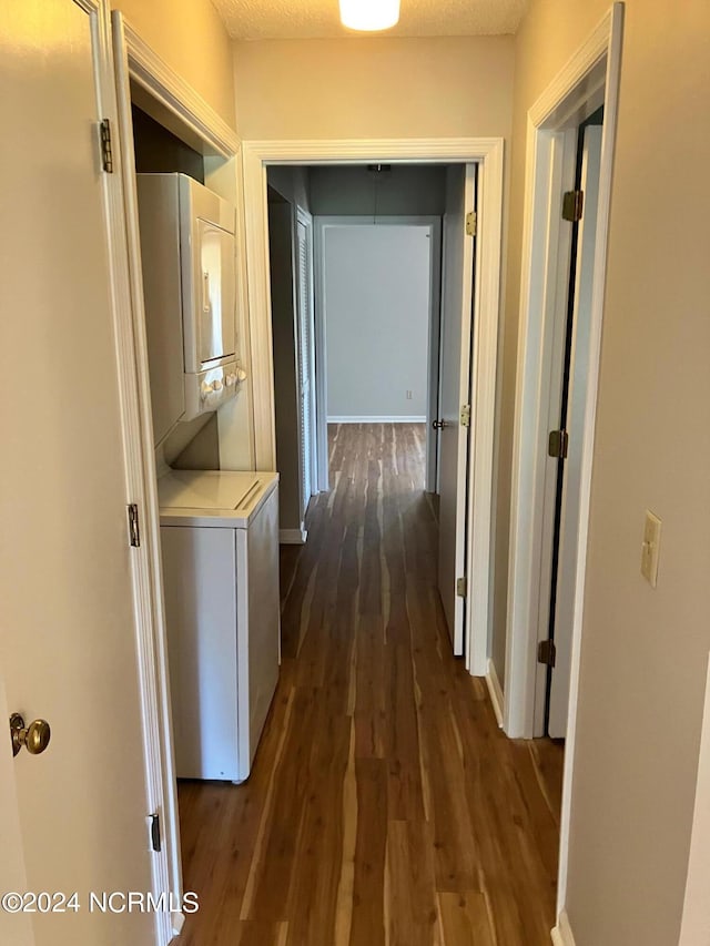 hall with dark wood-style floors, baseboards, and stacked washing maching and dryer