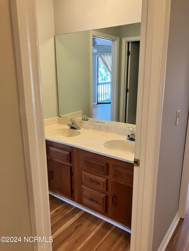 bathroom featuring double vanity, wood finished floors, and a sink