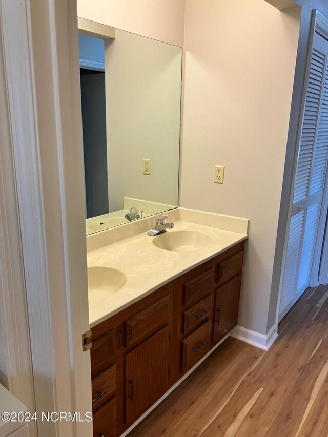 laundry room with sink, stacked washer / drying machine, and light wood-type flooring