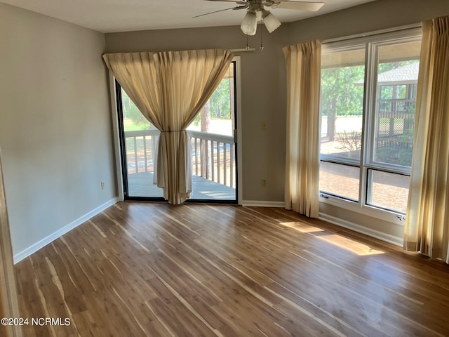 spare room featuring baseboards, plenty of natural light, wood finished floors, and a ceiling fan