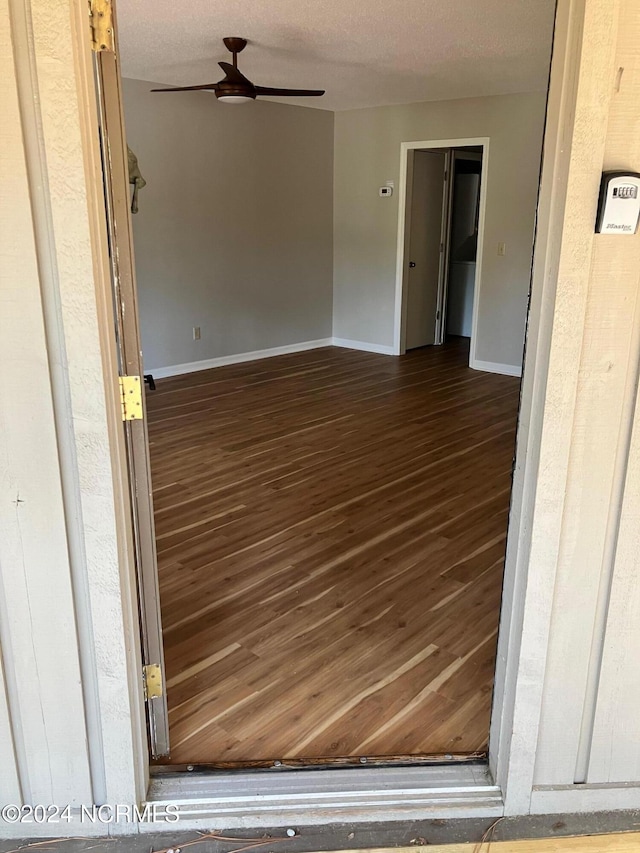 spare room featuring a textured ceiling, wood finished floors, baseboards, and ceiling fan