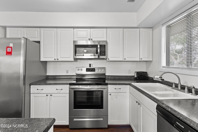 kitchen featuring stainless steel appliances, a sink, and white cabinets