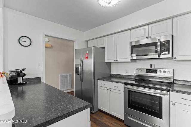 kitchen featuring dark wood finished floors, dark countertops, visible vents, appliances with stainless steel finishes, and white cabinets