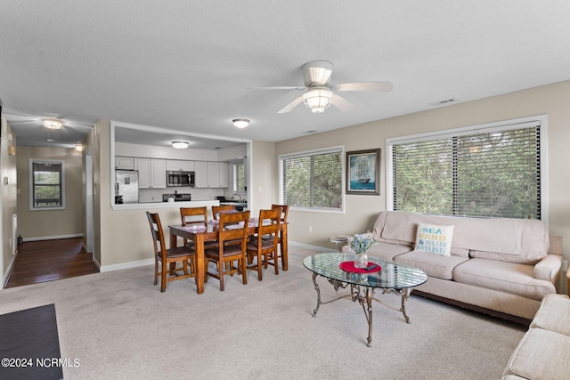 living room with light carpet, ceiling fan, visible vents, and a textured ceiling