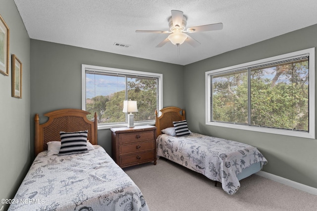 bedroom with visible vents, light carpet, baseboards, and a textured ceiling