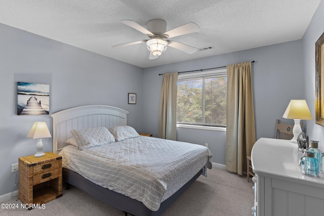 bedroom featuring light colored carpet, visible vents, a textured ceiling, and baseboards