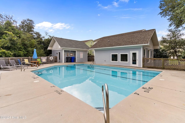 community pool featuring a patio area, fence, and an outdoor structure