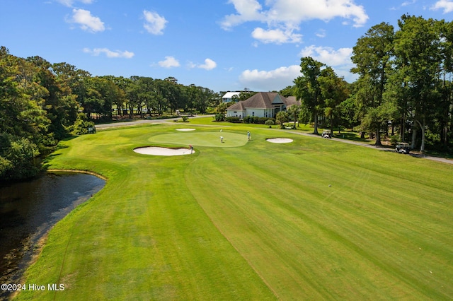 view of home's community with a water view, golf course view, and a yard