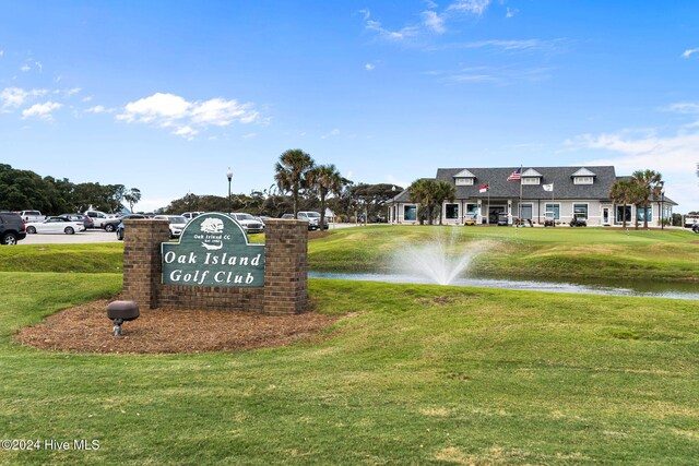 community sign featuring a water view and a lawn