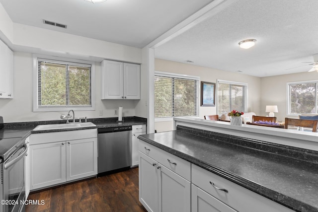 kitchen featuring appliances with stainless steel finishes, dark countertops, visible vents, and a sink