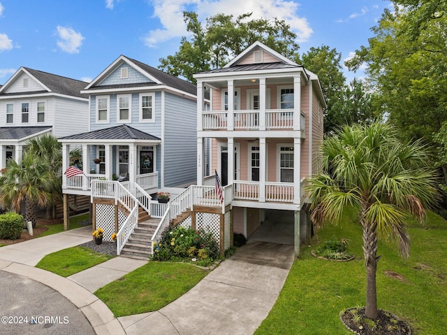 coastal inspired home featuring a front yard, a porch, a balcony, and driveway