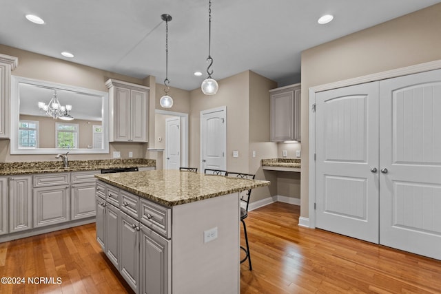 kitchen with light wood-style floors, gray cabinetry, a breakfast bar, and a center island