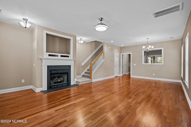 unfurnished living room featuring visible vents, a fireplace with flush hearth, baseboards, and wood finished floors