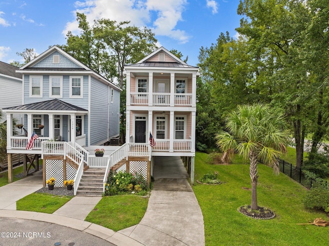 view of front facade featuring a balcony, a porch, a front yard, and a standing seam roof