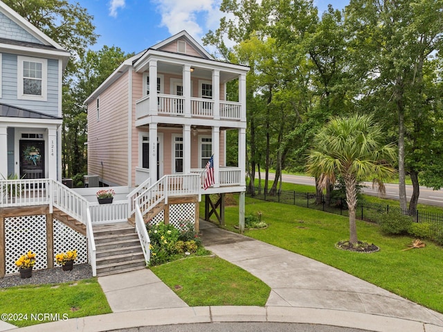 view of front of property featuring fence, covered porch, a front yard, a balcony, and stairs